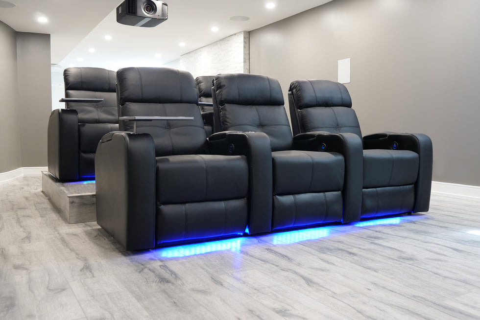 Two row of 3 sets of the Valencia Piacenza Home Theater Seating in a black color located in a basement home theater with a projector